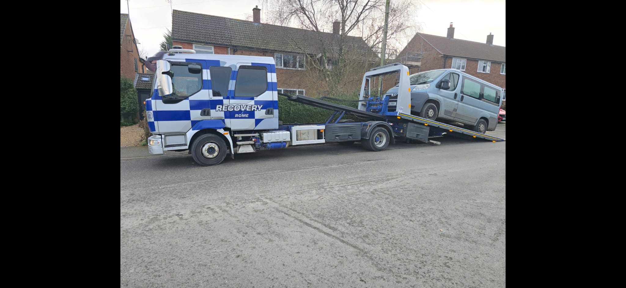 Recovery truck transporting a classic dark car