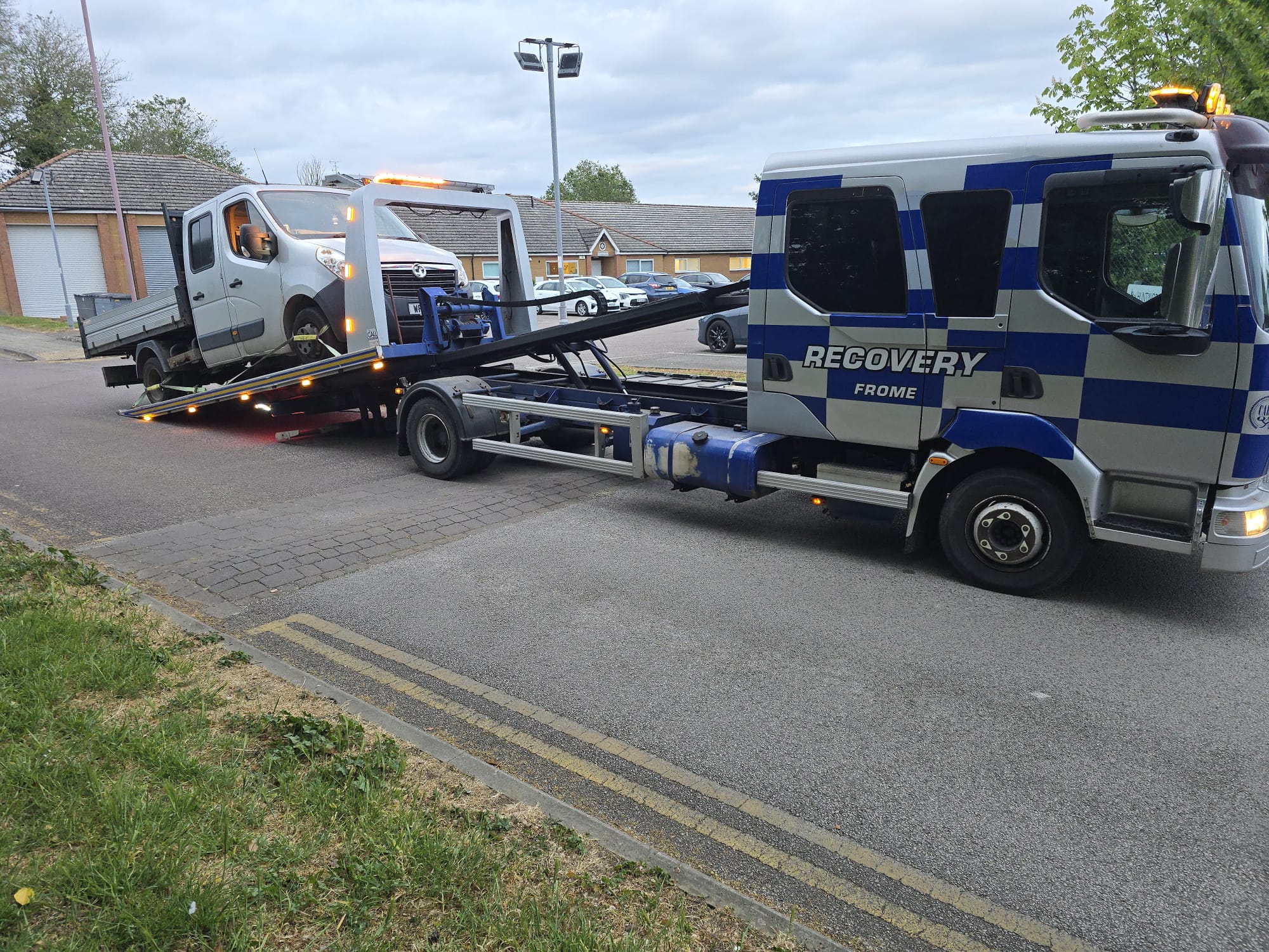 Recovery truck transporting a silver van on a residential street